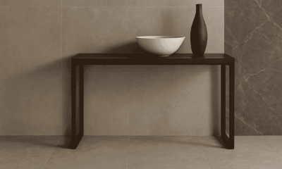Modern ceramic tile display in a stylish interior featuring Sodiceram products including beige wall tiles, light grey floor tiles, and a dark marble-patterned feature wall, with a minimalist wooden console and decorative objects.