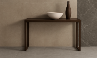 Modern ceramic tile display in a stylish interior featuring Sodiceram products including beige wall tiles, light grey floor tiles, and a dark marble-patterned feature wall, with a minimalist wooden console and decorative objects.